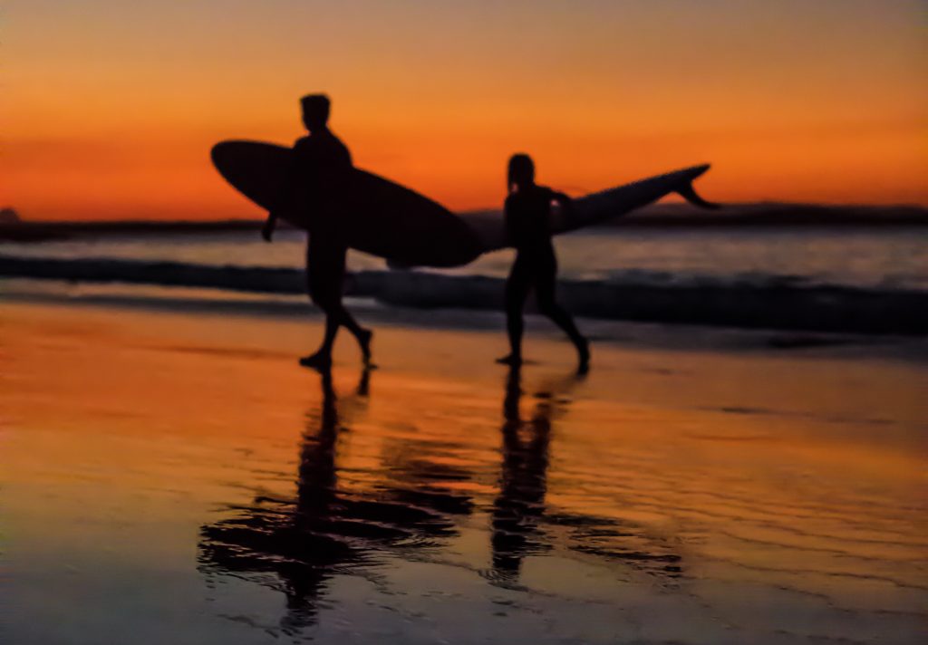 Deux surfeurs sur la plage de Noosa Heads au coucher de soleil dans la biosphère de la Sunshine Coast en Australie. Crédit : Kyle Roxas / Pexels.