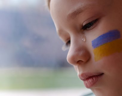 Enfant en pleurs avec le drapeau ukrainien sur la joue
