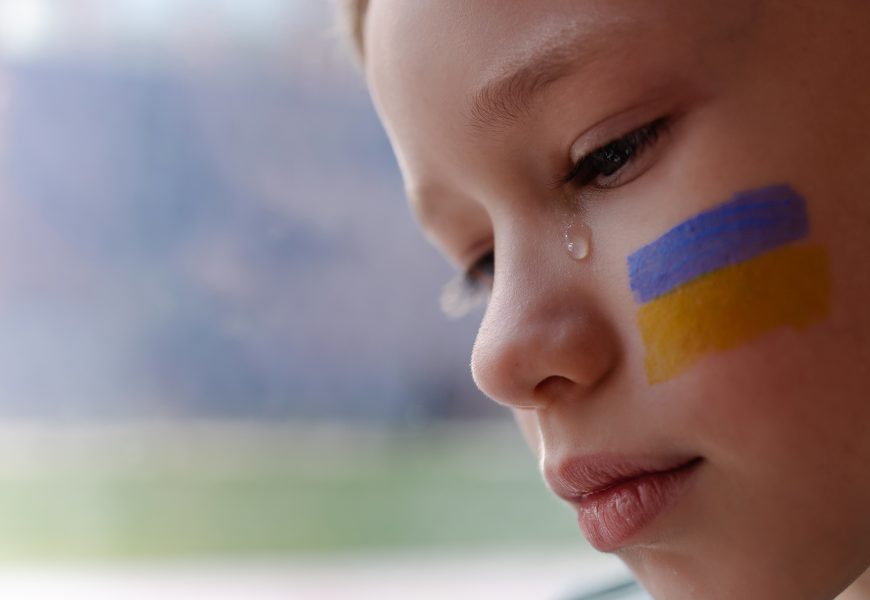 Enfant en pleurs avec le drapeau ukrainien sur la joue